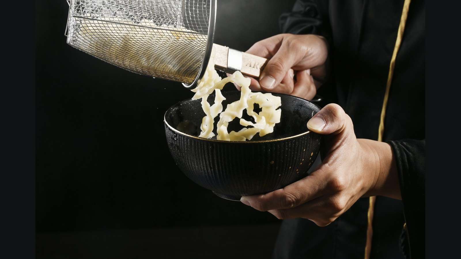 廚師將瀝乾麵條倒入黑色餐碗，料理製作過程攝影｜艾妃拉影像