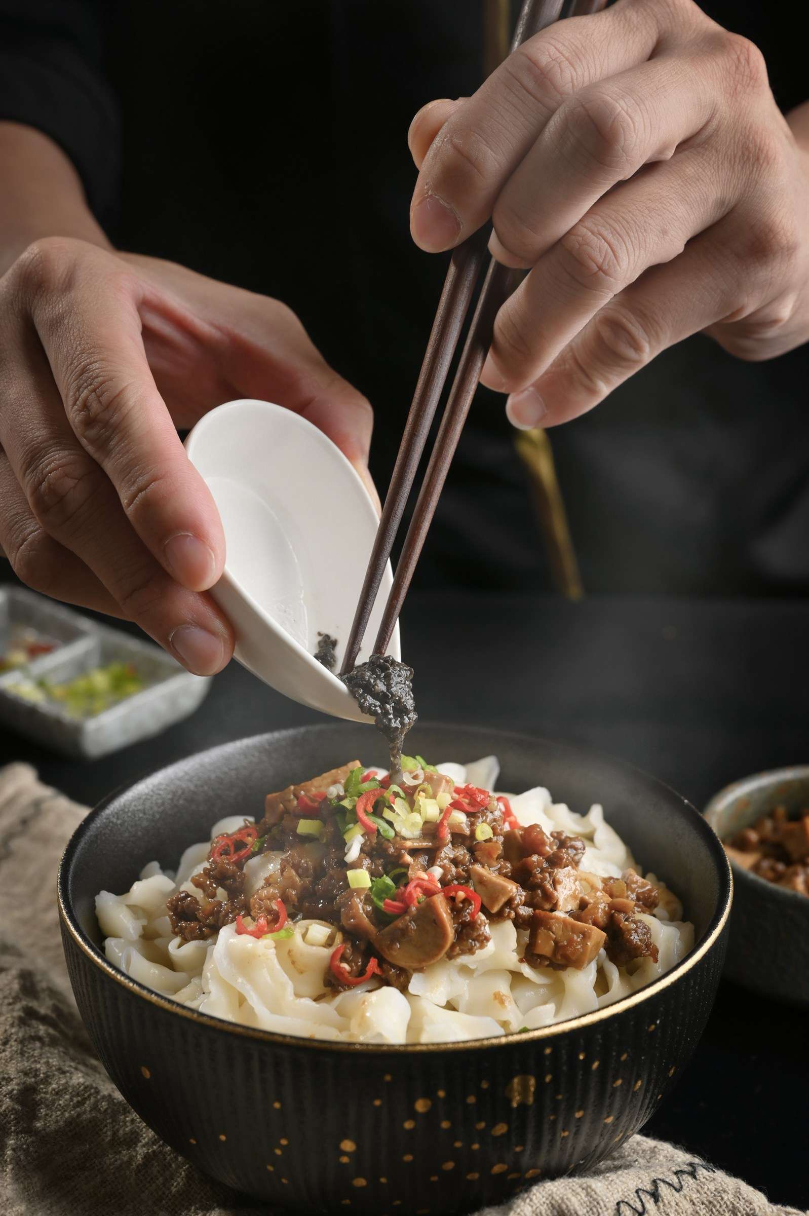 廚師以筷子將配料放上寬麵，完成擺盤｜艾妃拉影像